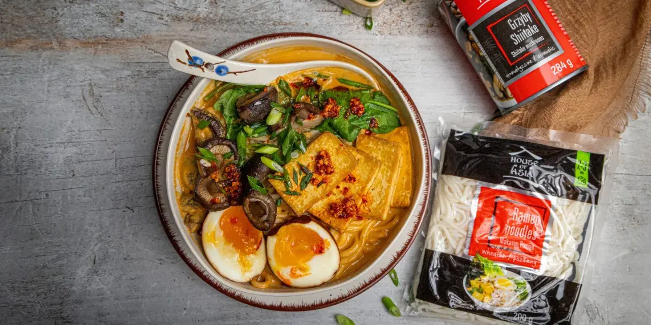 Szybki ramen przepis: miska pełna aromatycznego bulionu z grzybami shiitake, tofu, jajkiem i szczypiorkiem. Obok opakowanie makaronu i grzybów.