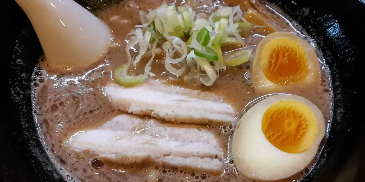 Aksamitny bulion, dwa połówki jajka na miękko, plastry boczku i szczypiorek tworzą apetyczny ramen z boczkiem.
