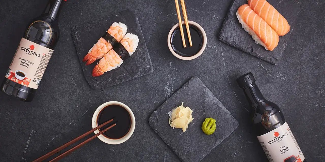 Słodki sos sojowy z butelki obok sushi z krewetkami i łososiem. Idealny dodatek do japońskich przysmaków.