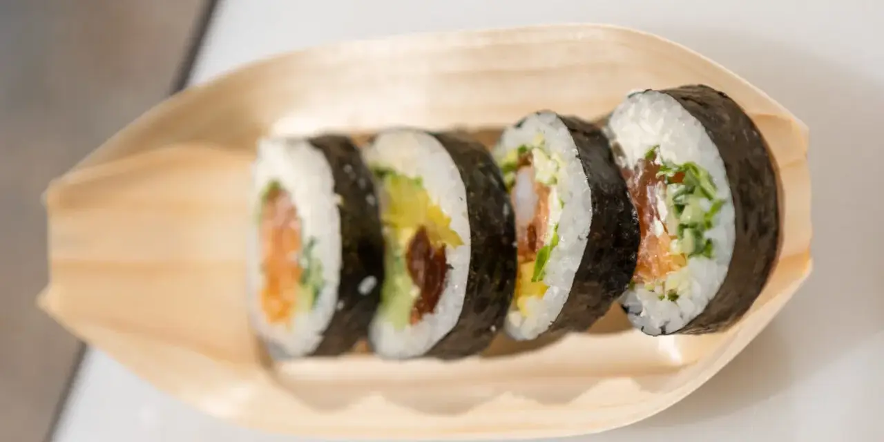 Pięć kawałków sushi z łososiem, awokado i krewetkami na drewnianej łódce. Różne rodzaje sushi nazwy.