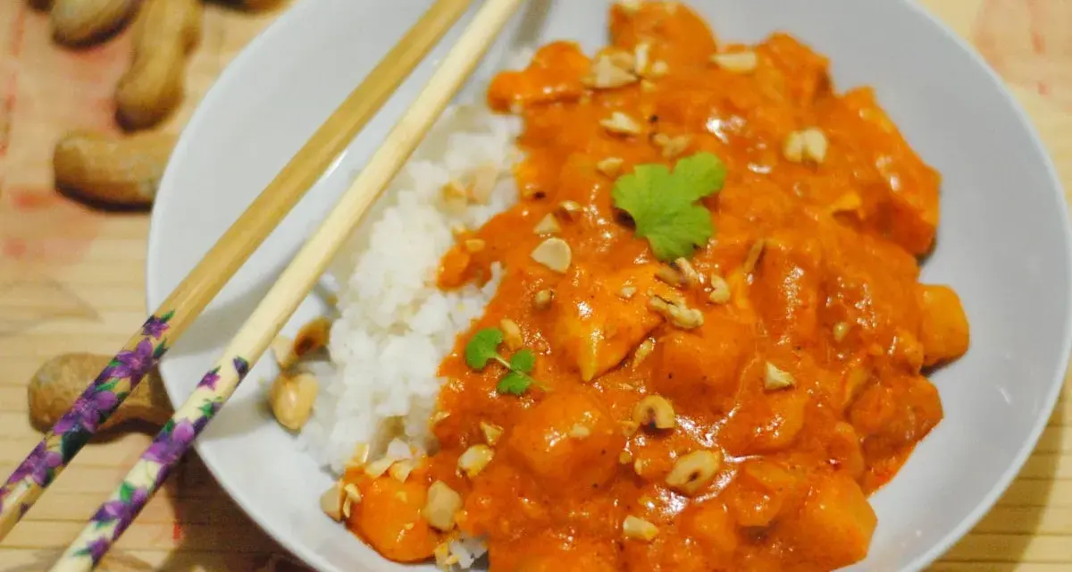 Pyszny massaman curry przepis: kurczak w kremowym sosie orzechowym z ryżem, posypany orzeszkami ziemnymi i kolendrą.