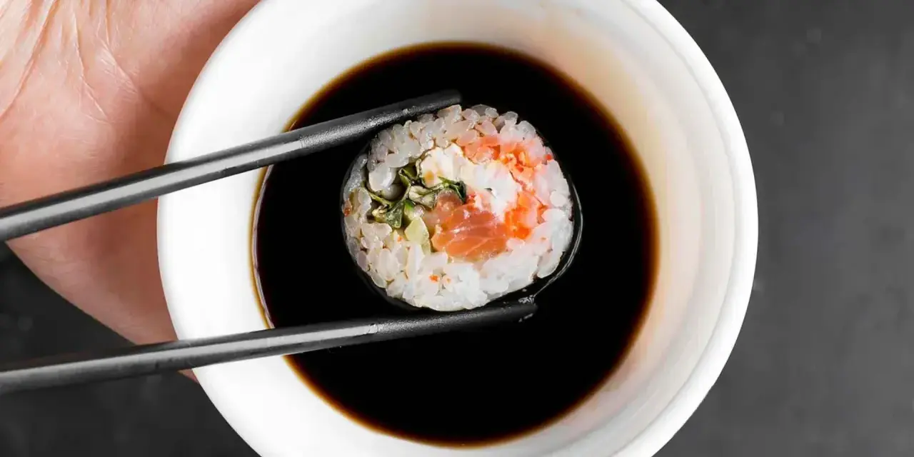 Pałeczkami zanurzam sushi z łososiem i kremowym nadzieniem w sosie sojowym. Idealny sojowy ser do sushi.