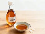 Butelka z etykietą "Mirin" i miseczka z bursztynowym płynem. To właśnie mirin, słodkie japońskie wino ryżowe, klucz do smaku wielu dań.