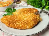 Dwa chrupiące kotlety z kurczaka w panko, podane na talerzu z sałatką z kapusty i marchewki.