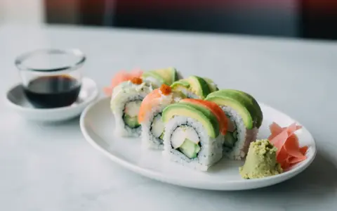 Uramaki california z awokado, krabem i ogórkiem, podane z wasabi i imbirem.