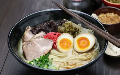 Parujący ramen z grubym makaronem, plastrami wieprzowiny, jajkiem na pół i szczypiorkiem. Idealny makaron do ramen to podstawa!
