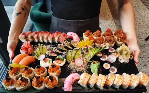 Taca pełna różnorodnego sushi: rolki z łososiem, tuńczykiem, krewetkami, a także nigiri. To właśnie sushi!