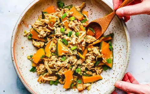 Mielone mięso z dynią i grzybami enoki, posypane szczypiorkiem. Danie wygląda jak składniki do tykwy sushi.