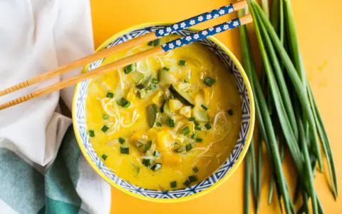 Aromaticzna zupa carry z makaronem ryżowym, warzywami i szczypiorkiem, gotowa do jedzenia pałeczkami.