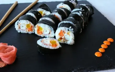 Rolka sushi philadelphia z łososiem, awokado i ogórkiem, podana z imbirem i wasabi.
