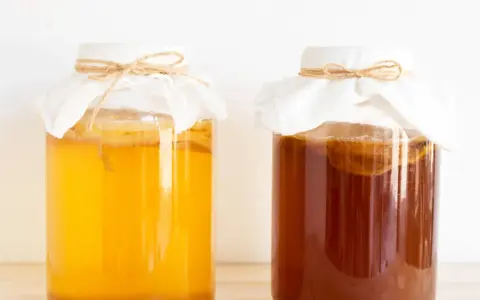 Dwa słoje z kombuchą, jeden jasnożółty, drugi ciemnobrązowy. Zastanawiasz się nad kombucha szkodliwość?
