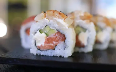Uranaki z łososiem, kremowym serkiem i ogórkiem, zwieńczone krewetką. Pyszne danie sushi.