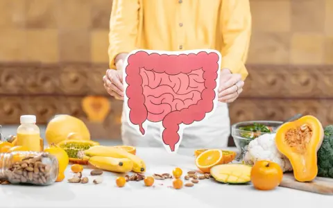 Osoba trzyma planszę z jelitami, wokół owoce i orzechy. Czy sos sojowy fodmap jest bezpieczny?