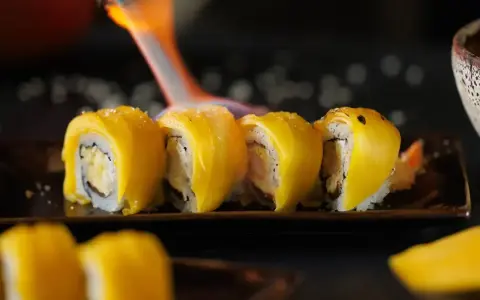 Płomień palnika opala sushi z mango, tworząc apetyczny wygląd.