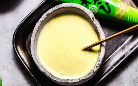 Kremowy majonez do sushi w miseczce, obok zielona tubka z wasabi. Idealny dodatek do Twoich ulubionych rolek.