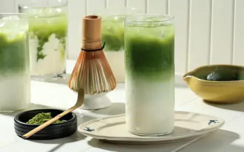 Zielone napoje matcha z lodem, bambusowa miotełka i proszek matcha.