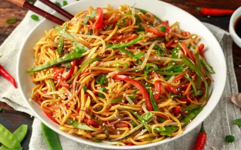 Miseczka makaronu chow mein z warzywami i pałeczkami.