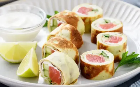 Sushi w naleśniku: rolki z łososiem, ogórkiem i serkiem, podane z dipem i limonką.