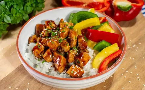 Pyszny kurczak z gotowym sosem teriyaki na ryżu, z kolorową papryką i szczypiorkiem.