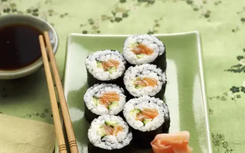 Sześć kawałków sushi z łososiem i ogórkiem, podanych z imbirem i sosem sojowym.