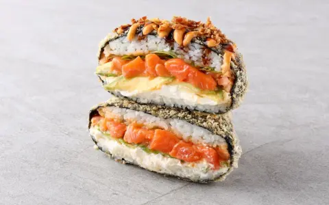 Sushiburger z łososiem, awokado i kremowym serkiem, otoczony chrupiącą panierką z ryżu i nori.