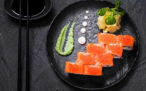 Roladki sushi z łososiem i ikrą, podane z zielonym, pikantnym wasabi prawdziwe, imbirem i sosem sojowym.