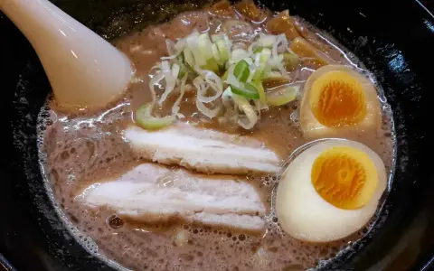 Aksamitny bulion, dwa połówki jajka na miękko, plastry boczku i szczypiorek tworzą apetyczny ramen z boczkiem.