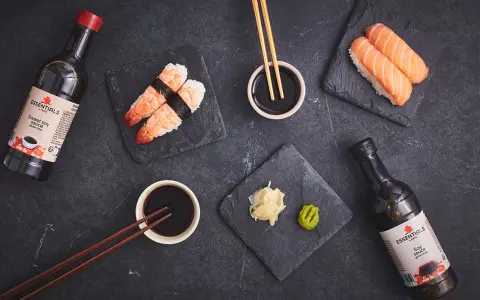 Słodki sos sojowy z butelki obok sushi z krewetkami i łososiem. Idealny dodatek do japońskich przysmaków.