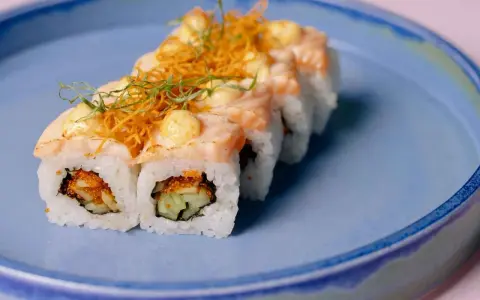 Roladki sushi z łososiem i chrupiącą posypką, z delikatnym akcentem, który przypominałby wasabi w ciąży, gdyby nie był to sos.