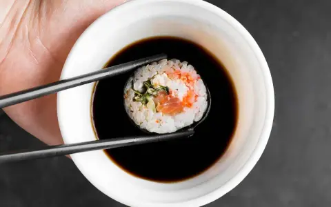 Pałeczkami zanurzam sushi z łososiem i kremowym nadzieniem w sosie sojowym. Idealny sojowy ser do sushi.