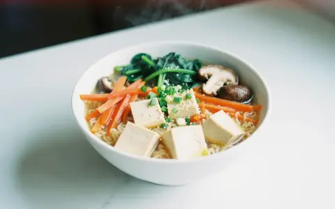 A miseczce ramenu z kostkami tofu, marchewką, szpinakiem i grzybami shiitake.