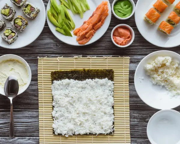 Idealny ryż do sushi jest kleisty i gotowy do zwinięcia z nori, łososiem i awokado.