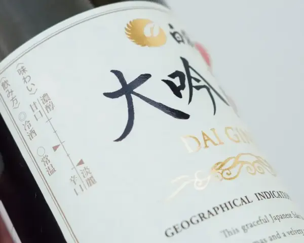 Butelka sake Dai Ginjo. Na etykiecie widnieje informacja o zawartości alkoholu, smakach i sposobie podania.