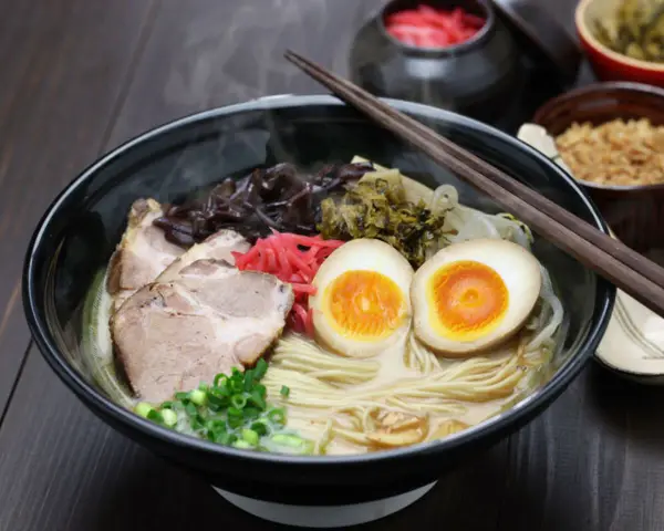 Parujący ramen z grubym makaronem, plastrami wieprzowiny, jajkiem na pół i szczypiorkiem. Idealny makaron do ramen to podstawa!