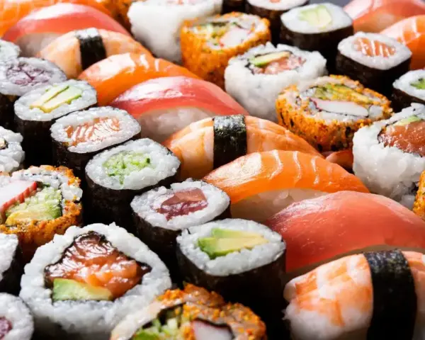 Różnorodne sushi, w tym rolki z łososiem i awokado, idealne dla dzieci. Czy dzieci mogą jeść sushi? Tak, jeśli wybierzemy łagodne składniki!