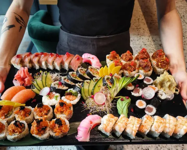 Taca pełna różnorodnego sushi: rolki z łososiem, tuńczykiem, krewetkami, a także nigiri. To właśnie sushi!