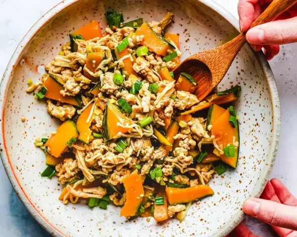 Mielone mięso z dynią i grzybami enoki, posypane szczypiorkiem. Danie wygląda jak składniki do tykwy sushi.
