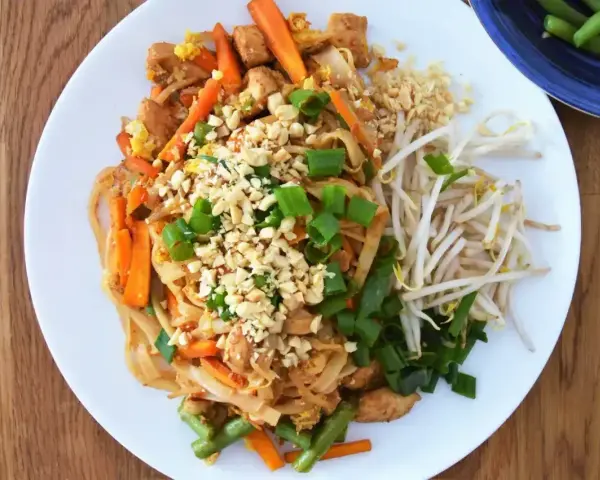 Pyszny pad thai oryginalny przepis z kurczakiem, warzywami i orzeszkami ziemnymi.