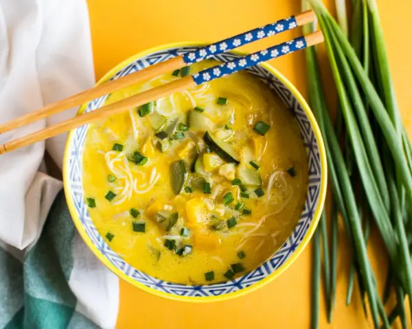 Aromaticzna zupa carry z makaronem ryżowym, warzywami i szczypiorkiem, gotowa do jedzenia pałeczkami.