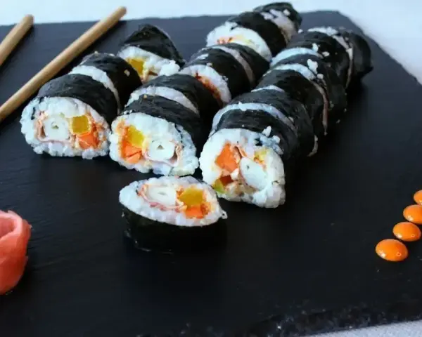 Rolka sushi philadelphia z łososiem, awokado i ogórkiem, podana z imbirem i wasabi.