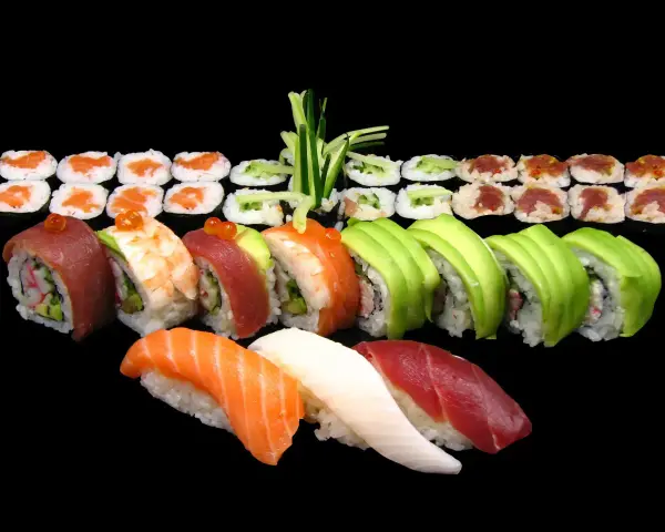 Różnorodne sushi: nigiri z łososiem, tuńczykiem i kalmarem, rolki z awokado, krewetką, tuńczykiem i krabem. Idealne na początek przygody, jak jeść sushi.