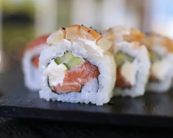 Uranaki z łososiem, kremowym serkiem i ogórkiem, zwieńczone krewetką. Pyszne danie sushi.