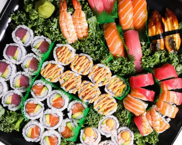 Taca pełna sushi z Japonii: rolki z tuńczykiem i awokado, łososiem, krewetkami, nigiri z łososiem, tuńczykiem i węgorzem.