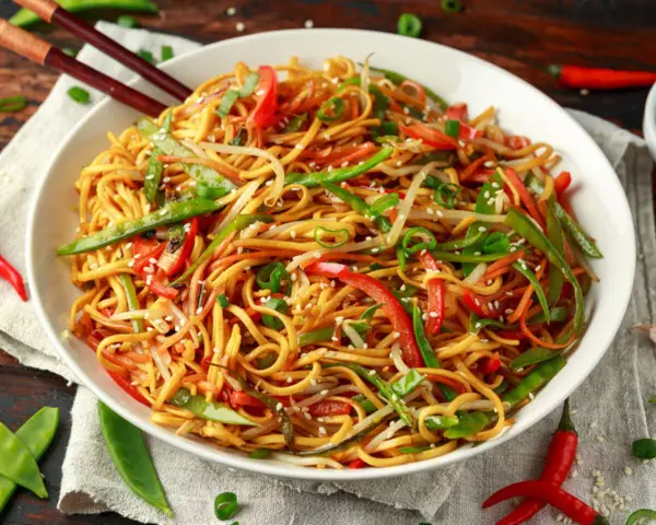 Miseczka makaronu chow mein z warzywami i pałeczkami.