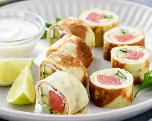 Sushi w naleśniku: rolki z łososiem, ogórkiem i serkiem, podane z dipem i limonką.