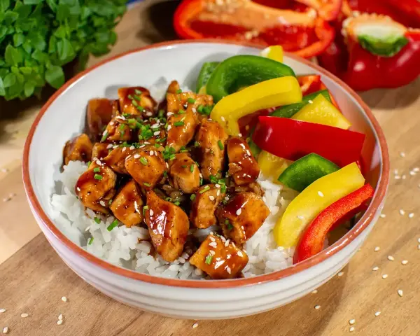 Pyszny kurczak z gotowym sosem teriyaki na ryżu, z kolorową papryką i szczypiorkiem.