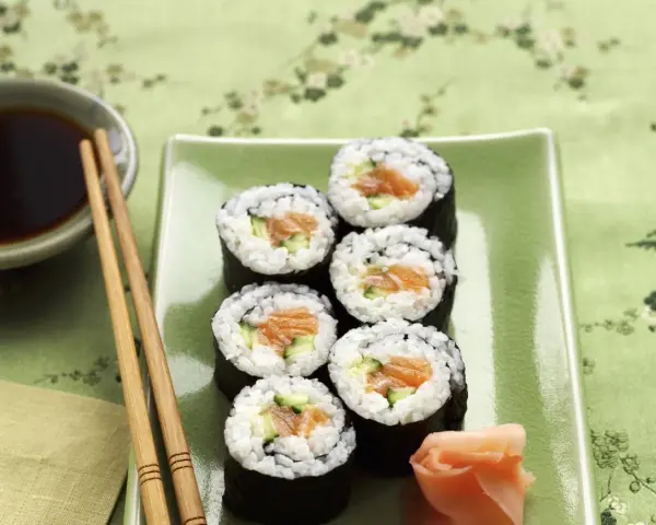Sześć kawałków sushi z łososiem i ogórkiem, podanych z imbirem i sosem sojowym.