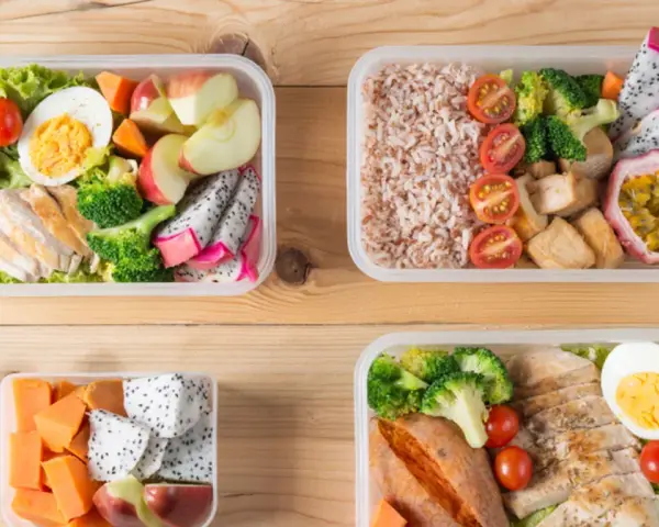 Cztery pudełka bento z kurczakiem, ryżem, warzywami i owocami. Idealne na zdrowy lunch, pokazują, bento co to jest.