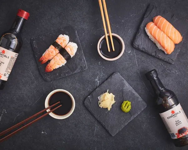 Słodki sos sojowy z butelki obok sushi z krewetkami i łososiem. Idealny dodatek do japońskich przysmaków.