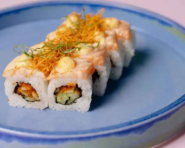Roladki sushi z łososiem i chrupiącą posypką, z delikatnym akcentem, który przypominałby wasabi w ciąży, gdyby nie był to sos.